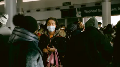 A woman wears a mask during the Covid-19 pandemic in a large crowd at a transit station in New York City.